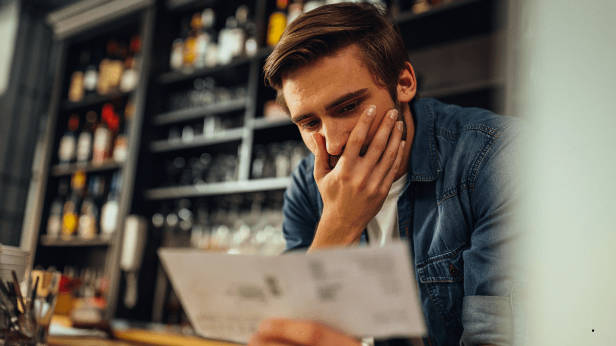 Australian café owner reviewing payment costs at a counter - card terminal, calculator, and printed statement