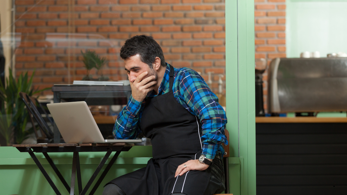Small business owner reviewing card payment costs at a café counter with a printed statement